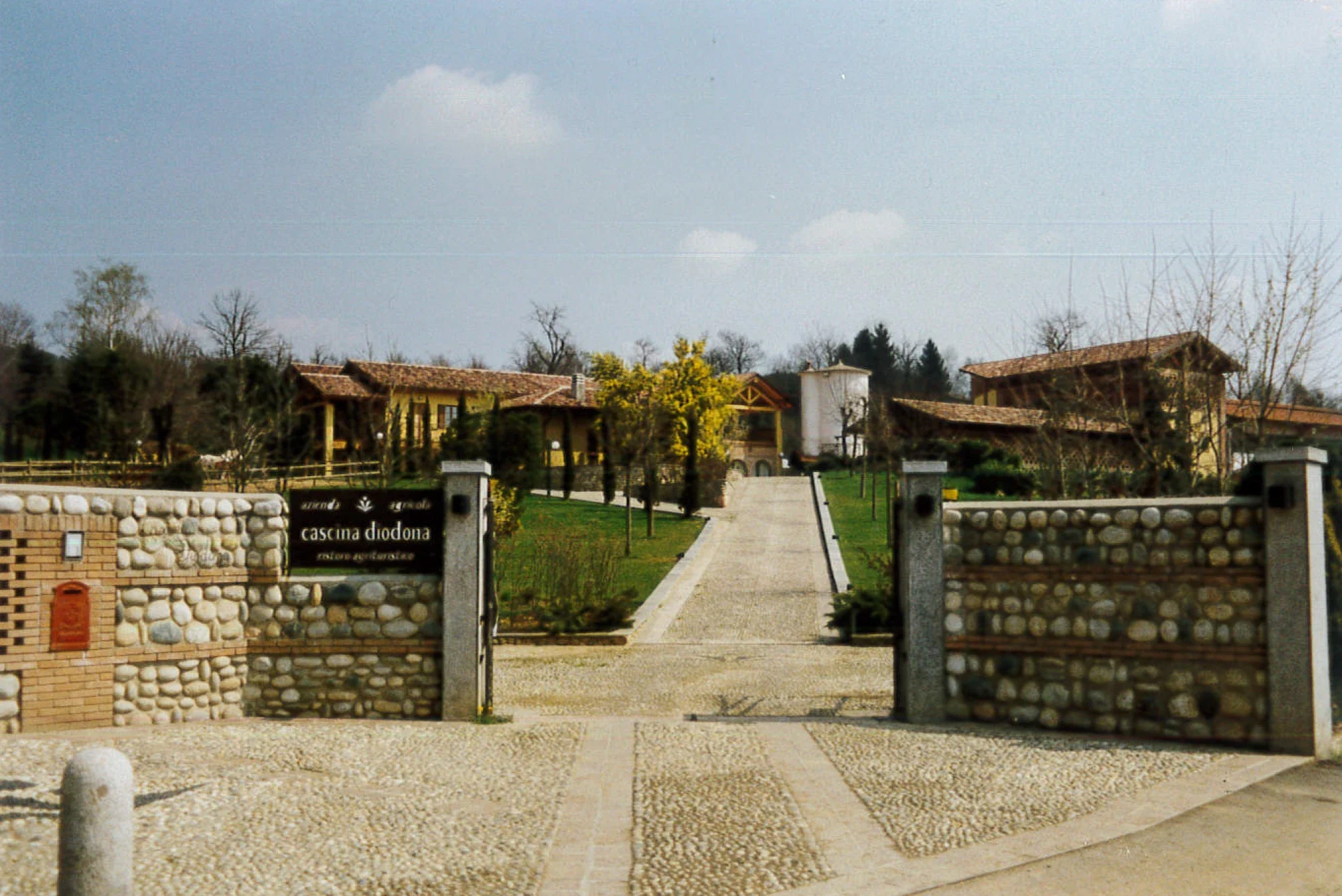 Ingresso storico della cascina Corte Gelsi con il vialetto e l’insegna originale
