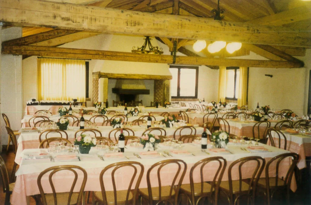 Sala storica del ristorante Corte Gelsi allestita per un banchetto con tavoli imbanditi
