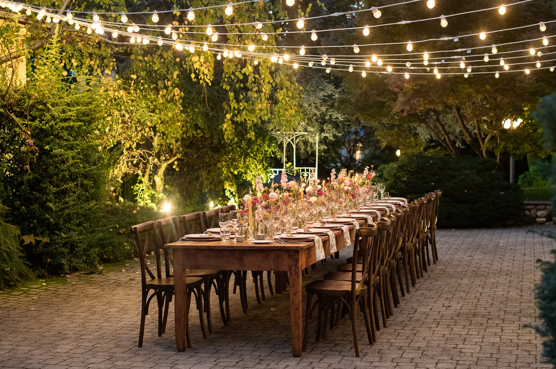 Allestimento cortile del ristorante Corte Gelsi per una cena con tavolo imperiale e fiori